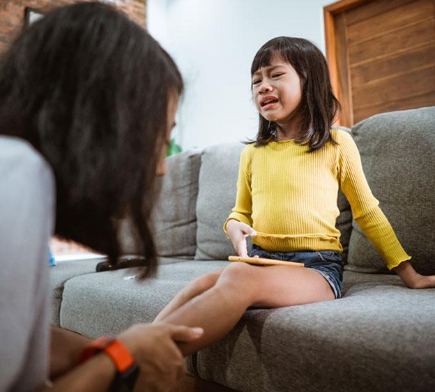 A mother inspecting her little girl's injured leg