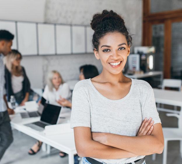 Young Black woman smiling surrounded by co-workers in an office